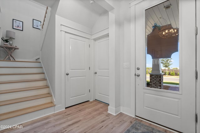 foyer with light wood-type flooring and vaulted ceiling