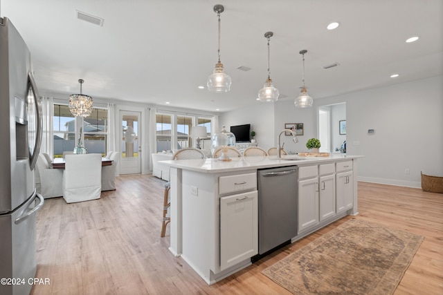 kitchen featuring a wealth of natural light, white cabinetry, a kitchen island with sink, and appliances with stainless steel finishes