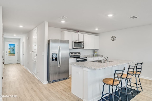 kitchen featuring white cabinetry, sink, light hardwood / wood-style flooring, a center island with sink, and appliances with stainless steel finishes