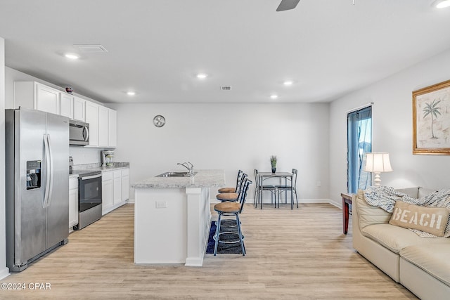 kitchen with white cabinets, an island with sink, light hardwood / wood-style floors, and appliances with stainless steel finishes