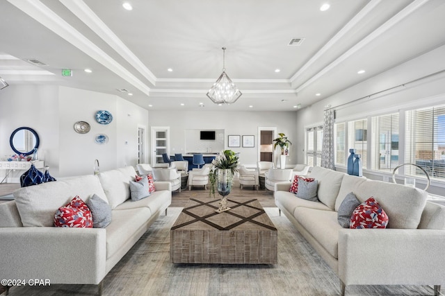 living room with hardwood / wood-style floors, a raised ceiling, and a chandelier