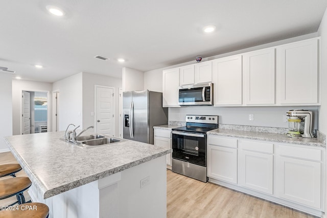 kitchen featuring white cabinetry, sink, a breakfast bar area, appliances with stainless steel finishes, and light wood-type flooring