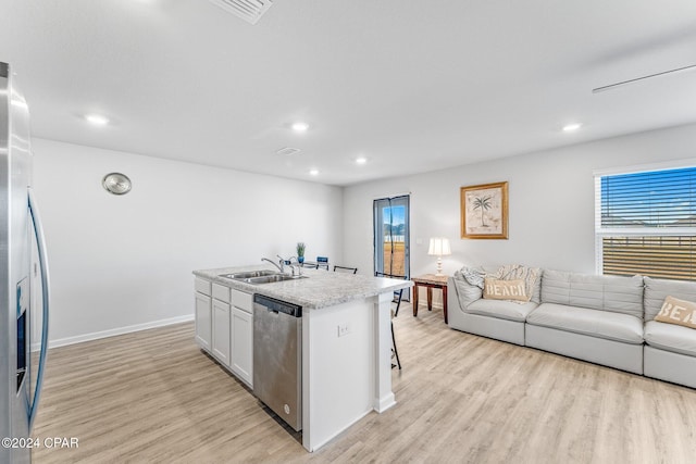 kitchen with appliances with stainless steel finishes, sink, a center island with sink, white cabinets, and light hardwood / wood-style floors