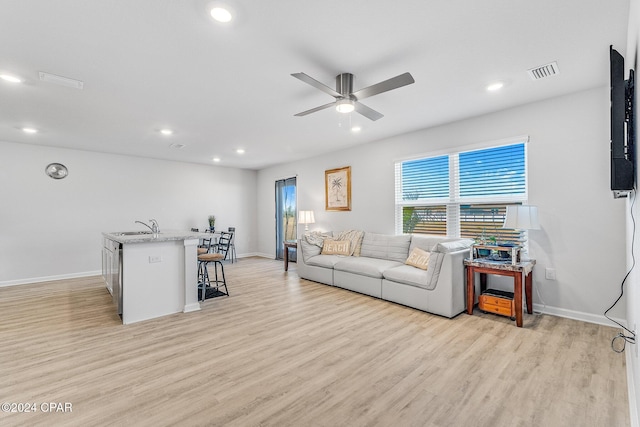 living room featuring light hardwood / wood-style floors, ceiling fan, and sink