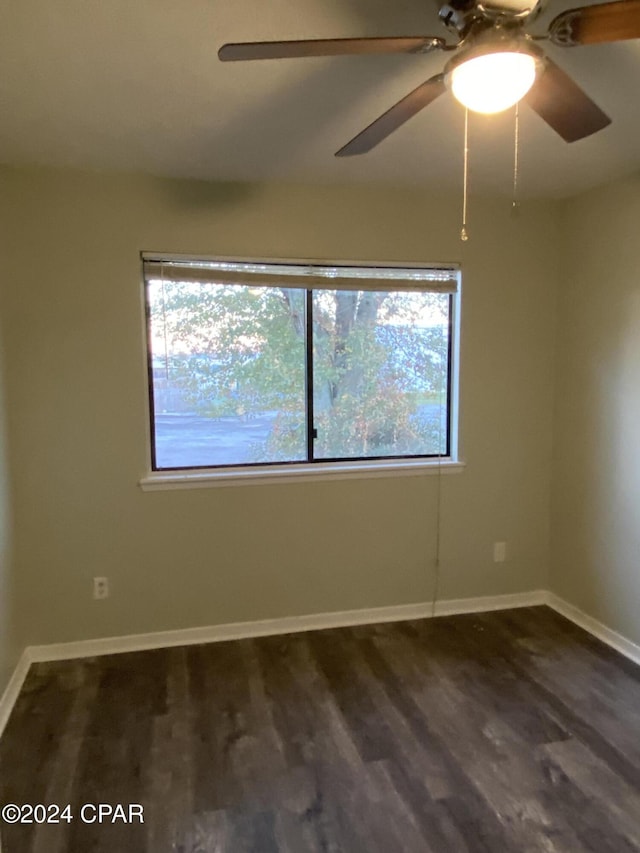 empty room featuring a wealth of natural light, ceiling fan, and dark hardwood / wood-style floors