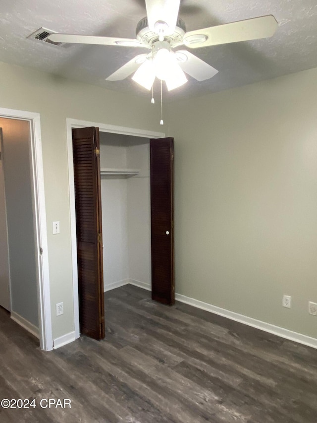 unfurnished bedroom featuring ceiling fan, a closet, and dark wood-type flooring