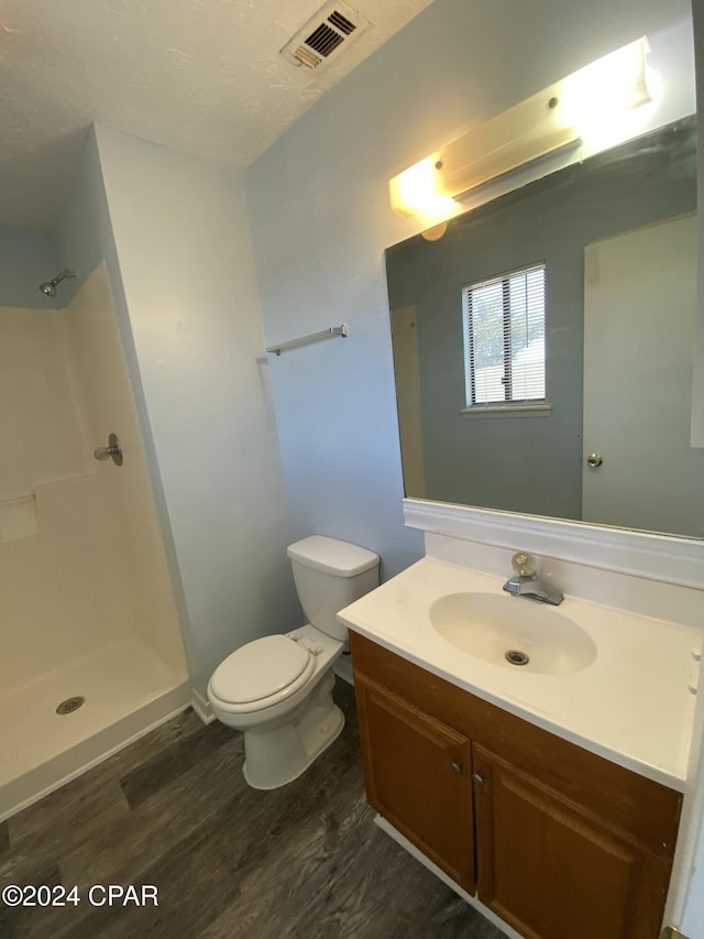 bathroom with a shower, hardwood / wood-style floors, vanity, and toilet