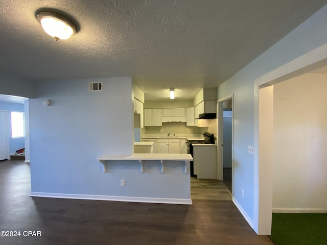 kitchen featuring white cabinets, a kitchen breakfast bar, sink, electric range, and kitchen peninsula