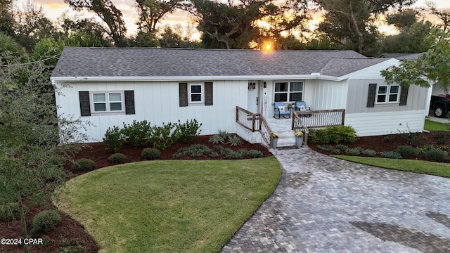 single story home with covered porch and a lawn