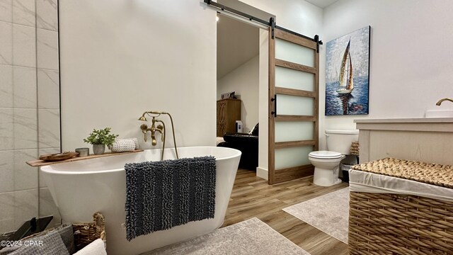 bathroom with hardwood / wood-style flooring, toilet, and a bath