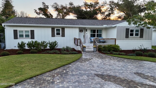 single story home with a lawn, cooling unit, and a porch