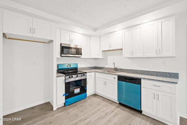 kitchen featuring appliances with stainless steel finishes, a textured ceiling, sink, white cabinets, and light hardwood / wood-style floors