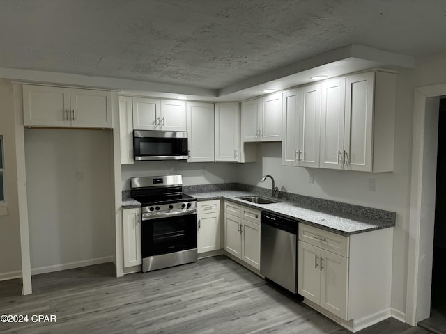 kitchen with sink, white cabinets, stainless steel appliances, and light wood-type flooring