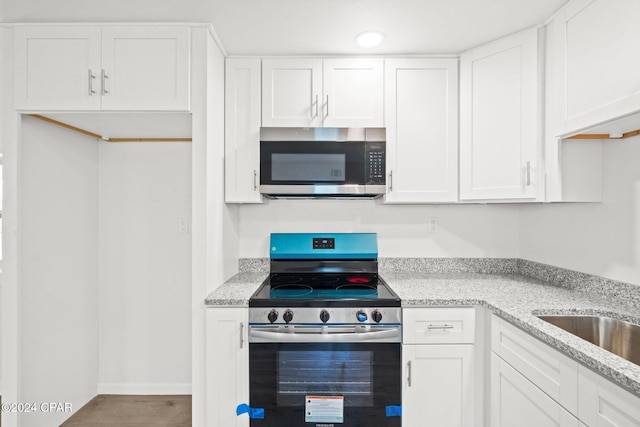 kitchen featuring light stone countertops, white cabinetry, sink, and appliances with stainless steel finishes