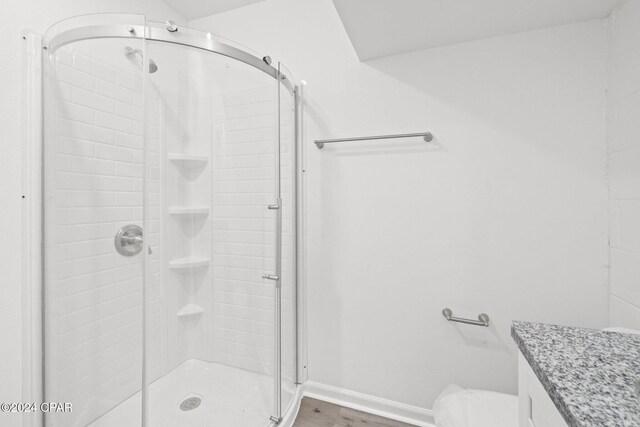 bathroom with hardwood / wood-style floors, vanity, toilet, and walk in shower