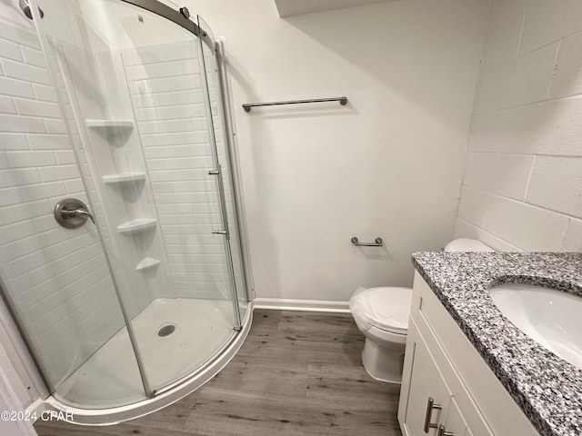 bathroom with hardwood / wood-style floors, toilet, an enclosed shower, and vanity