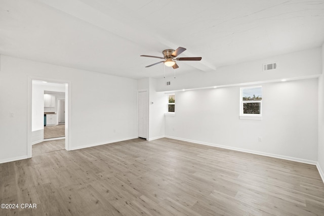 empty room featuring beamed ceiling, ceiling fan, and light hardwood / wood-style floors