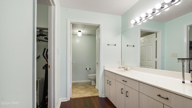 bathroom featuring radiator, wood-type flooring, vanity, toilet, and a textured ceiling