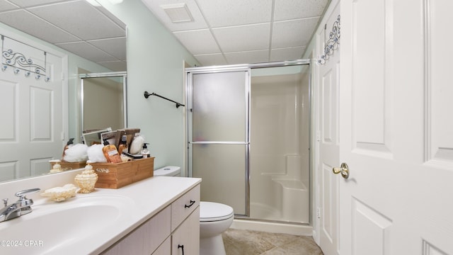 bathroom featuring a paneled ceiling, tile patterned flooring, vanity, a shower with shower door, and toilet