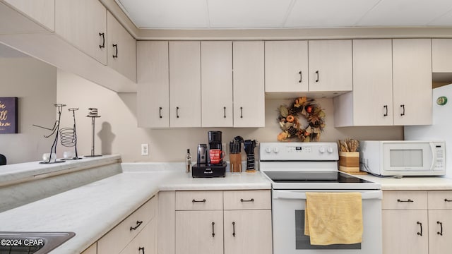 kitchen featuring cream cabinets, white appliances, and sink