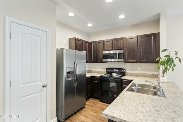 kitchen featuring kitchen peninsula, dark brown cabinets, stainless steel appliances, sink, and light hardwood / wood-style floors