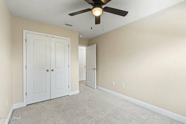 unfurnished bedroom featuring ceiling fan, light colored carpet, and a closet