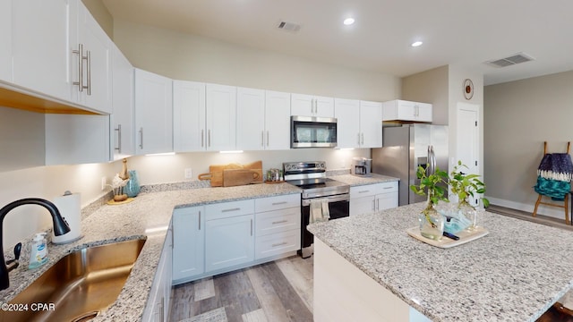 kitchen featuring a center island, white cabinets, sink, light hardwood / wood-style flooring, and appliances with stainless steel finishes