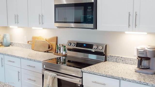 kitchen featuring light stone countertops, white cabinets, and stainless steel appliances