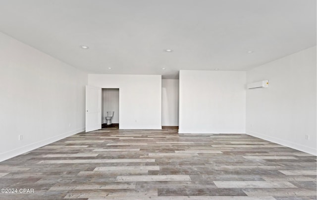 empty room featuring a wall mounted air conditioner and light hardwood / wood-style floors