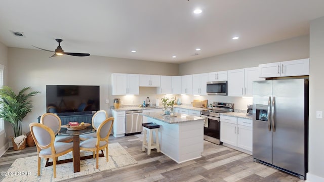 kitchen featuring a center island, sink, stainless steel appliances, white cabinets, and light wood-type flooring