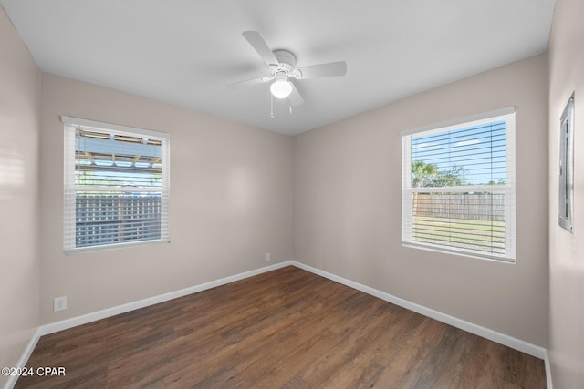 empty room featuring dark wood-type flooring, ceiling fan, and a wealth of natural light