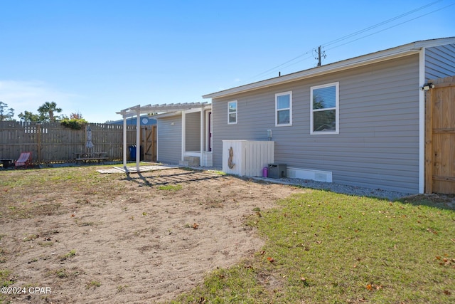 back of house with a pergola and a lawn