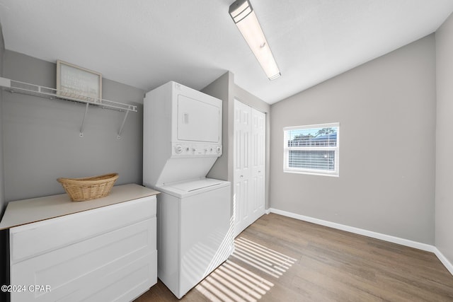 laundry room featuring stacked washing maching and dryer and light hardwood / wood-style floors