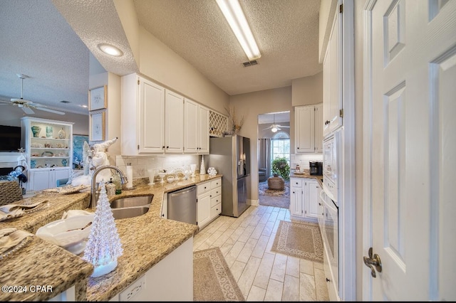 kitchen featuring white cabinets, light stone counters, stainless steel appliances, and a textured ceiling