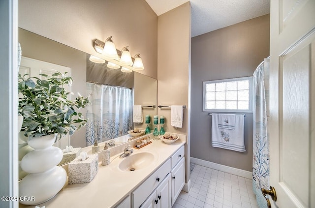 bathroom with tile patterned flooring, vanity, and a textured ceiling