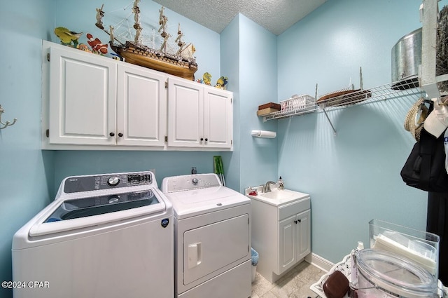 clothes washing area featuring sink, cabinets, a textured ceiling, and independent washer and dryer