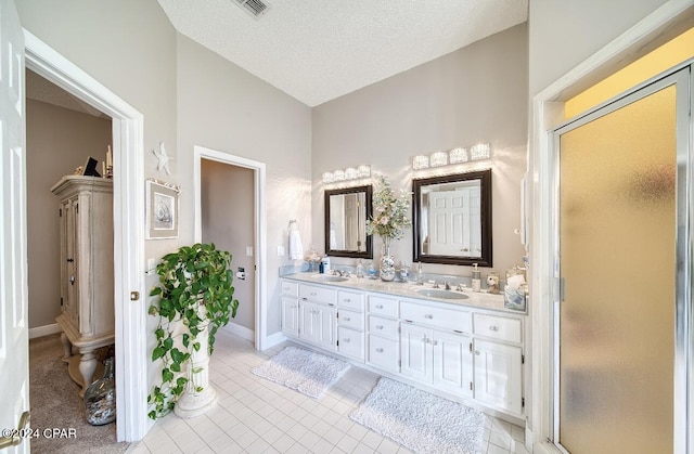 bathroom with tile patterned floors, lofted ceiling, a textured ceiling, vanity, and a shower with shower door