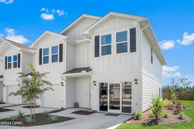 view of front of property featuring a garage, driveway, fence, and board and batten siding