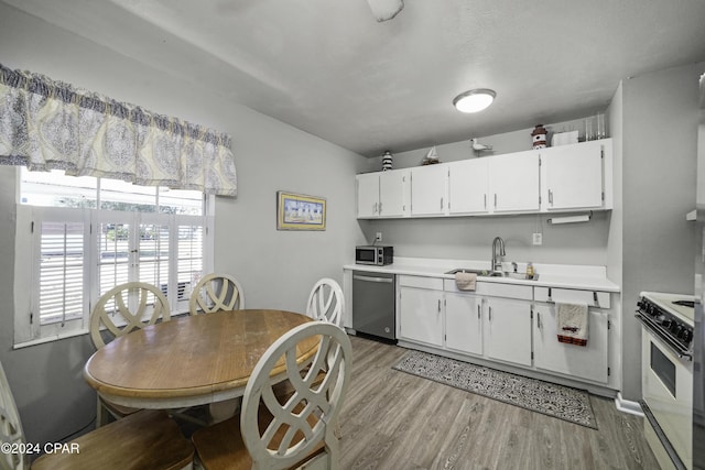 kitchen with appliances with stainless steel finishes, light hardwood / wood-style floors, white cabinetry, and sink