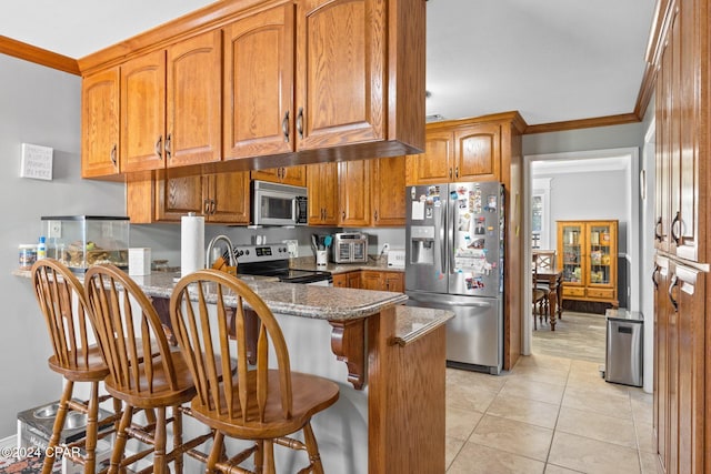 kitchen featuring stainless steel appliances, kitchen peninsula, dark stone counters, a kitchen bar, and ornamental molding