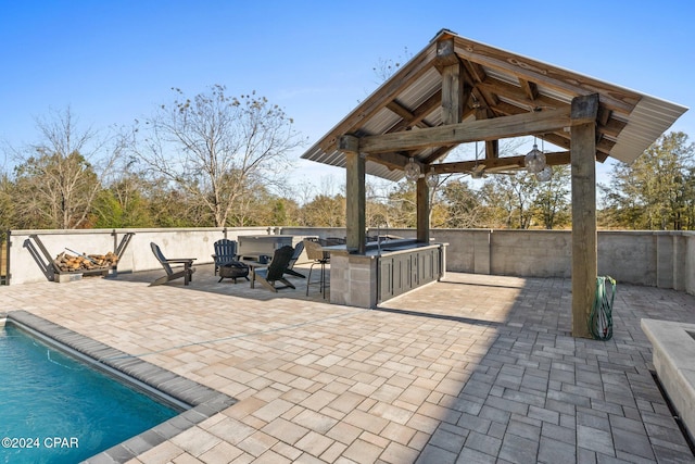 view of patio with a gazebo, area for grilling, a bar, and a fenced in pool