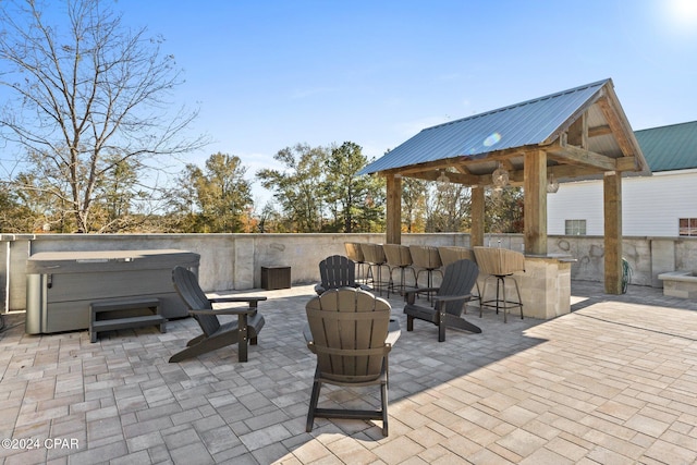 view of patio with a gazebo, a bar, and a hot tub