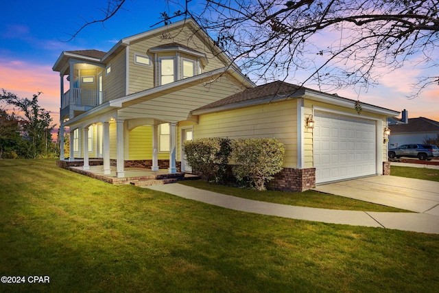 view of front of home featuring a porch, a balcony, a yard, and a garage