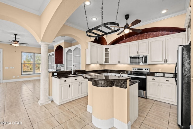 kitchen featuring white cabinets, appliances with stainless steel finishes, a kitchen island, and ornate columns