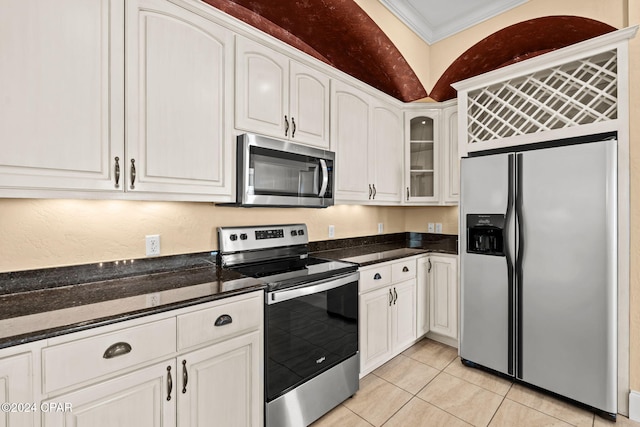 kitchen featuring white cabinets, appliances with stainless steel finishes, light tile patterned floors, and ornamental molding