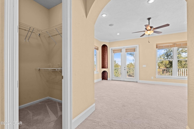 spacious closet featuring ceiling fan, french doors, and light colored carpet