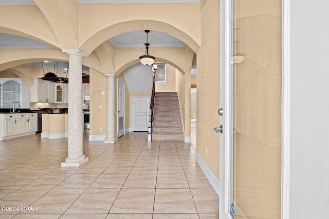 entryway featuring ornate columns, crown molding, sink, and light tile patterned floors