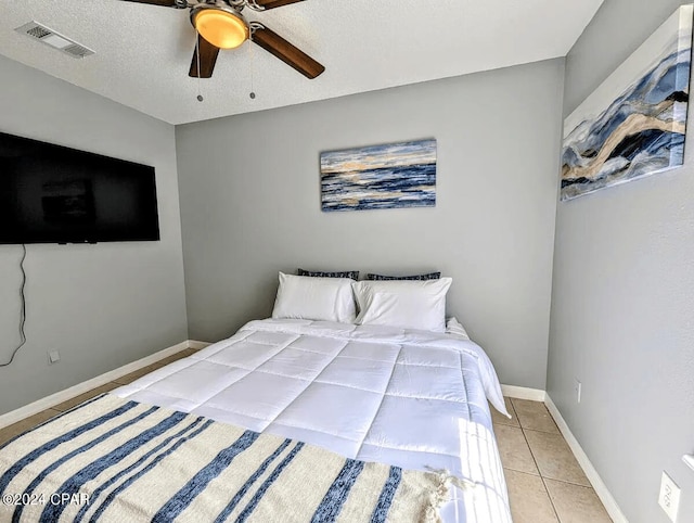 tiled bedroom featuring ceiling fan and a textured ceiling