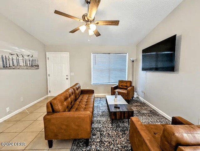 living room featuring a textured ceiling, ceiling fan, light tile patterned floors, and lofted ceiling