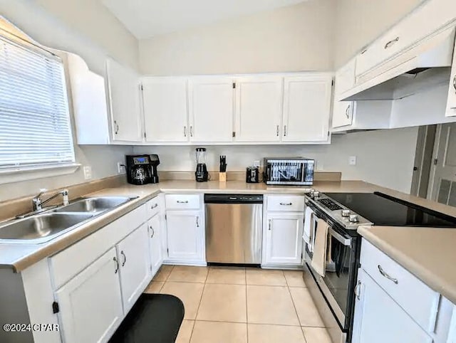 kitchen featuring sink, light tile patterned flooring, vaulted ceiling, white cabinets, and appliances with stainless steel finishes